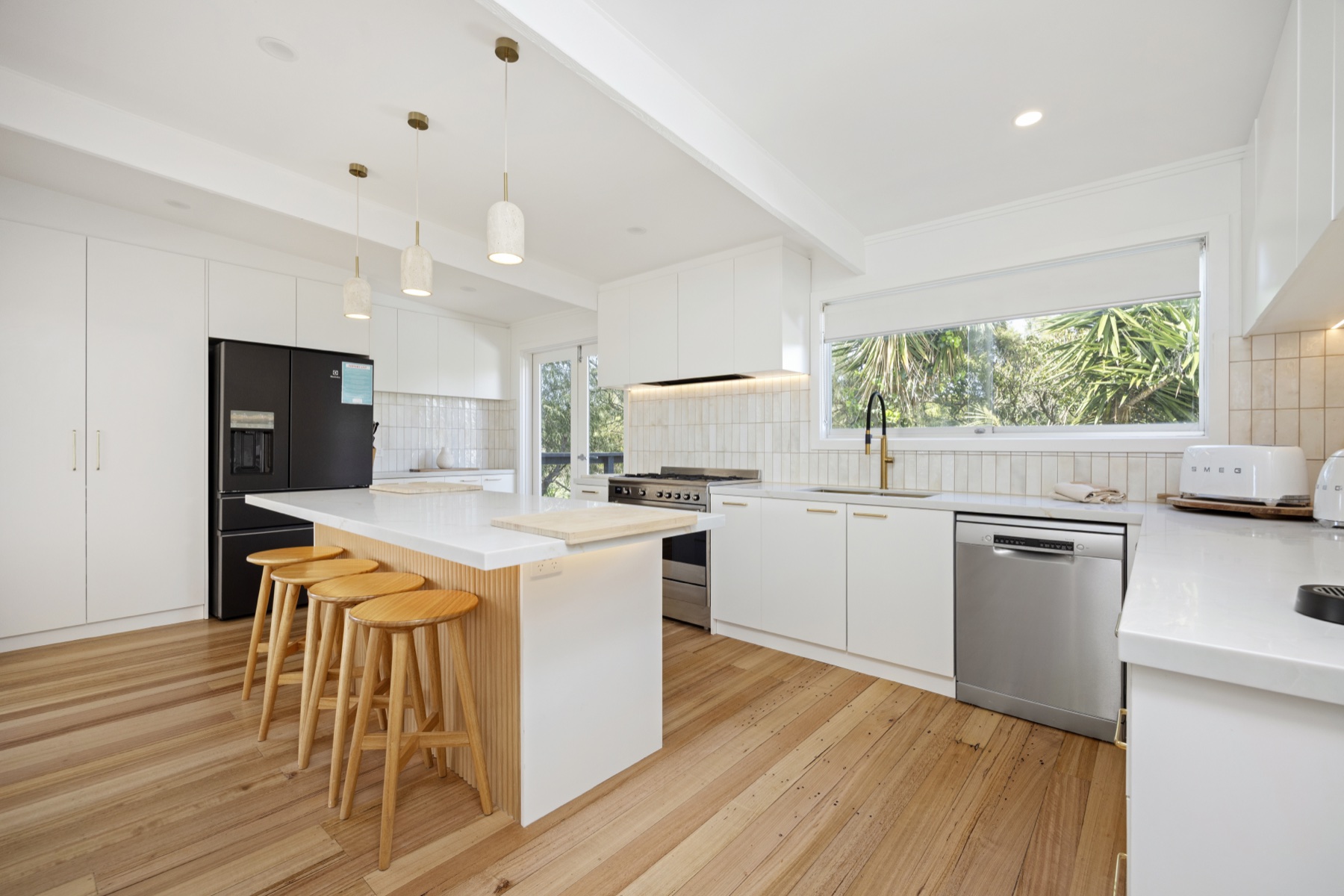 Open-plan white kitchen with island bench and timber floors